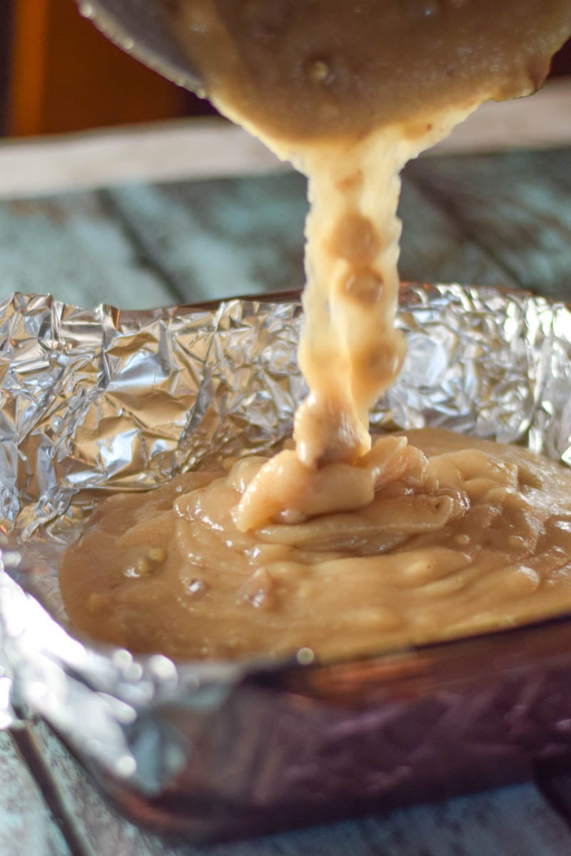 Pouring fudge into a foil lined square pan.