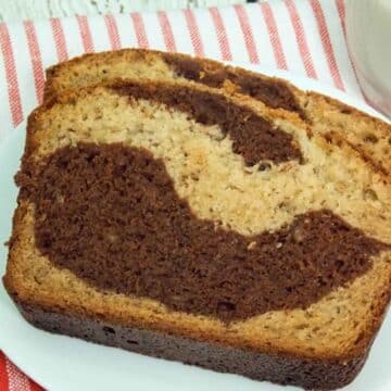 Upclose image of two slices of chocolate swirl banana bread on a white plate.