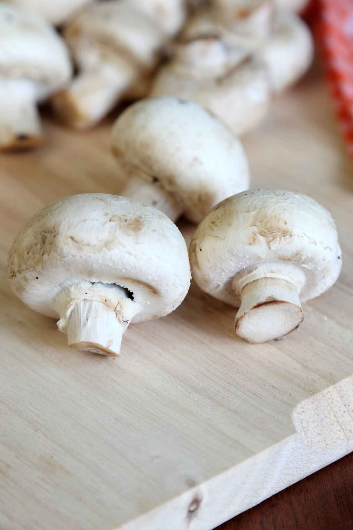 Button mushrooms on a wooden cutting board.