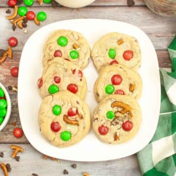 A white plate with 6 m&m pretzel cookies.