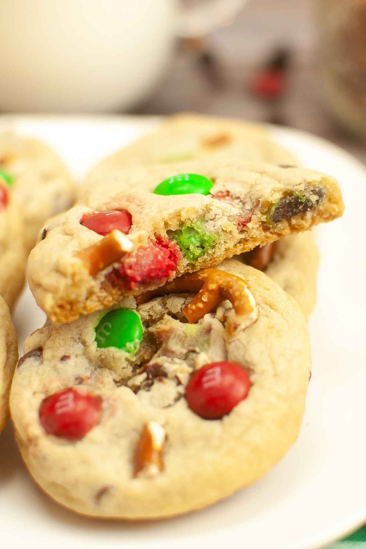 A stack of cookies with red and green chocolate coated candy, chocolate chips, and pretzels inside.