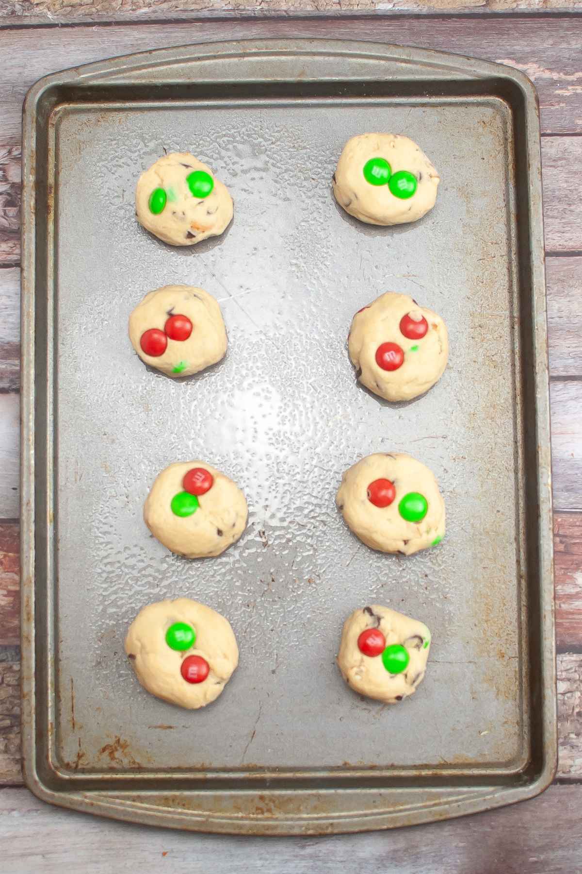 Eight balls of cookie dough on a prepared baking sheet.