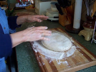 Mom's hand patting down and shaping the doughnut dough