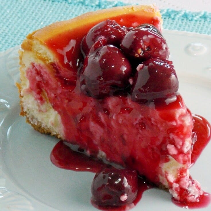 One slice of NY Style Cheesecake on a plate topped with cherry topping.