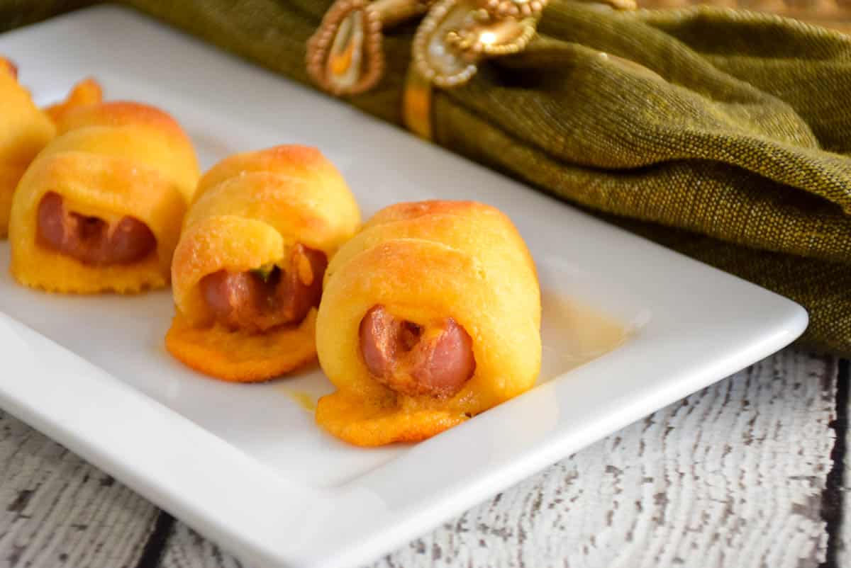 Pastry Wrapped Cheesy Cocktail Franks on a white serving tray.