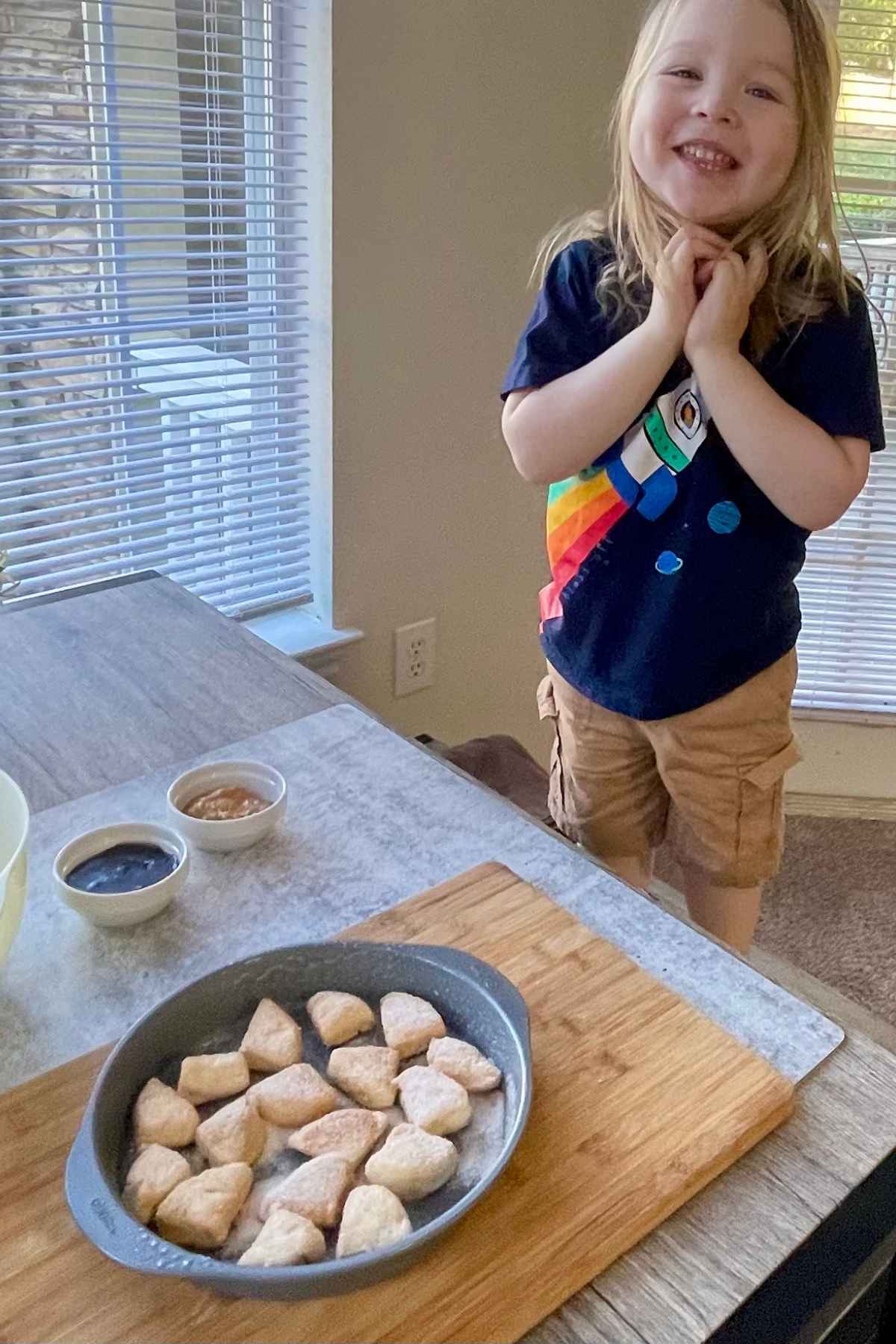 Grandson on table bench watching the Peanut Butter and Jelly Monkey Bread being made.