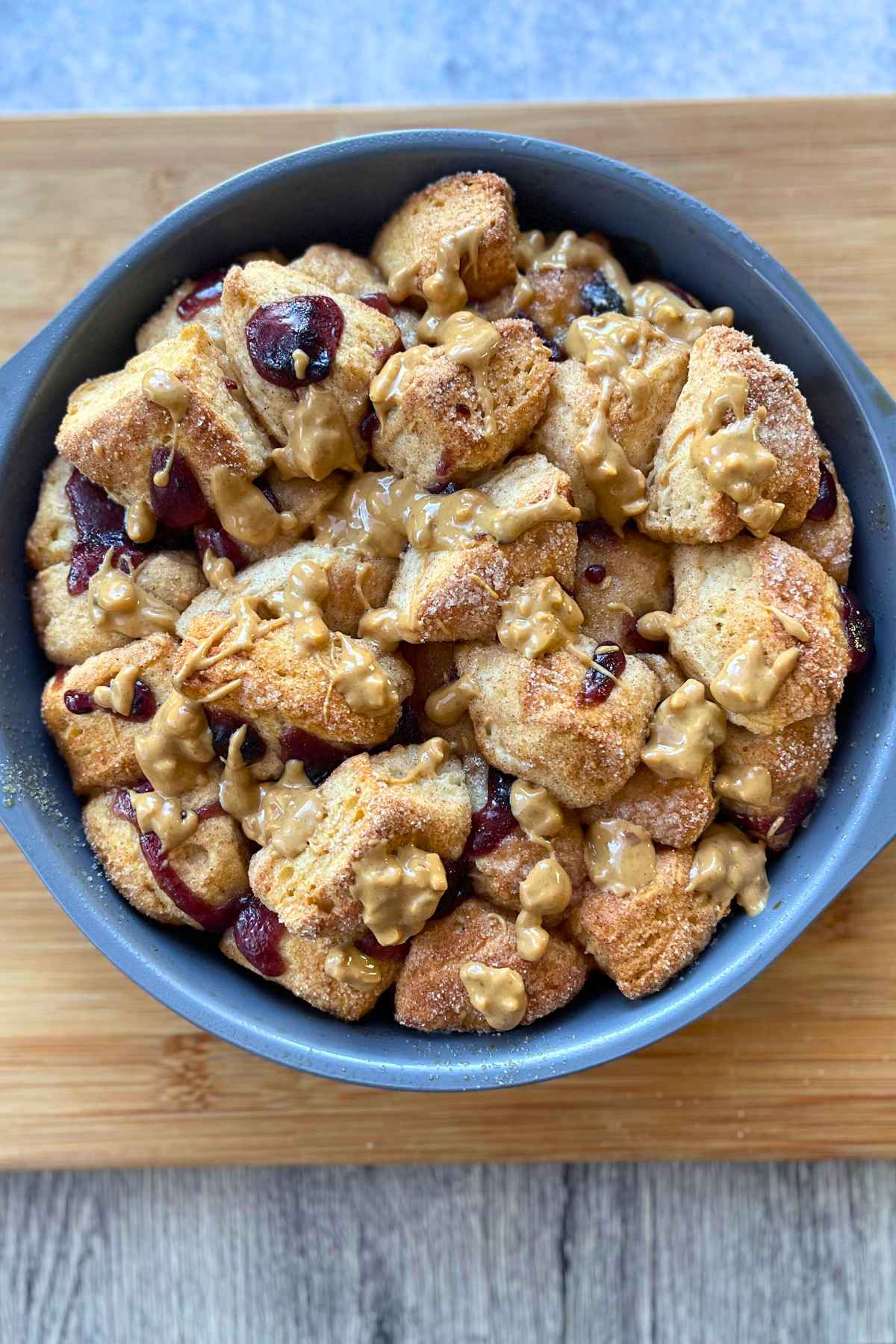 Baked monkey bread with peanut butter drizzle on top of golden brown pieces of biscuit dough.