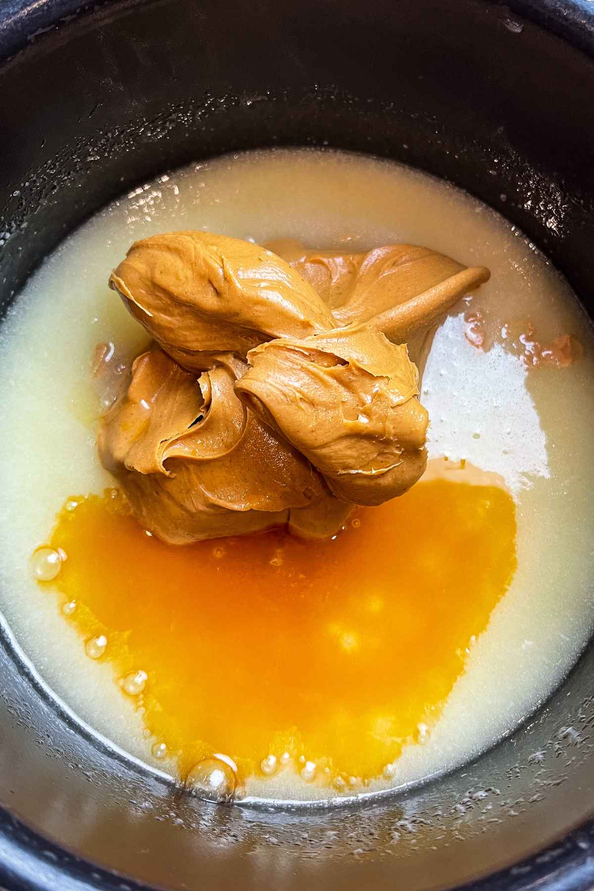 Peanut butter and vanilla on top of boiled sugar mixture in a saucepan.