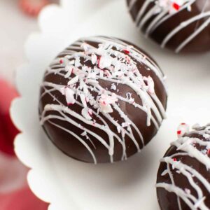 Upclose image of peppermint hot cocoa bomb on a white tray with white chocolate and crushed peppermints.