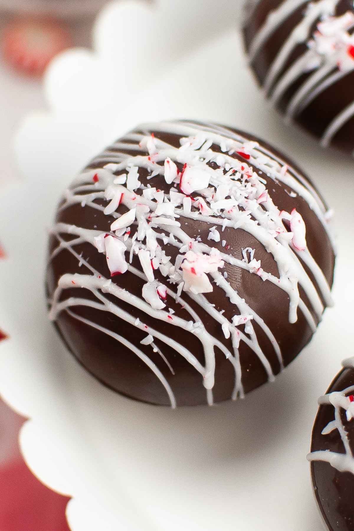 Upclose image of a peppermint hot cocoa bomb drizzled with white chocolate and crushed peppermint.