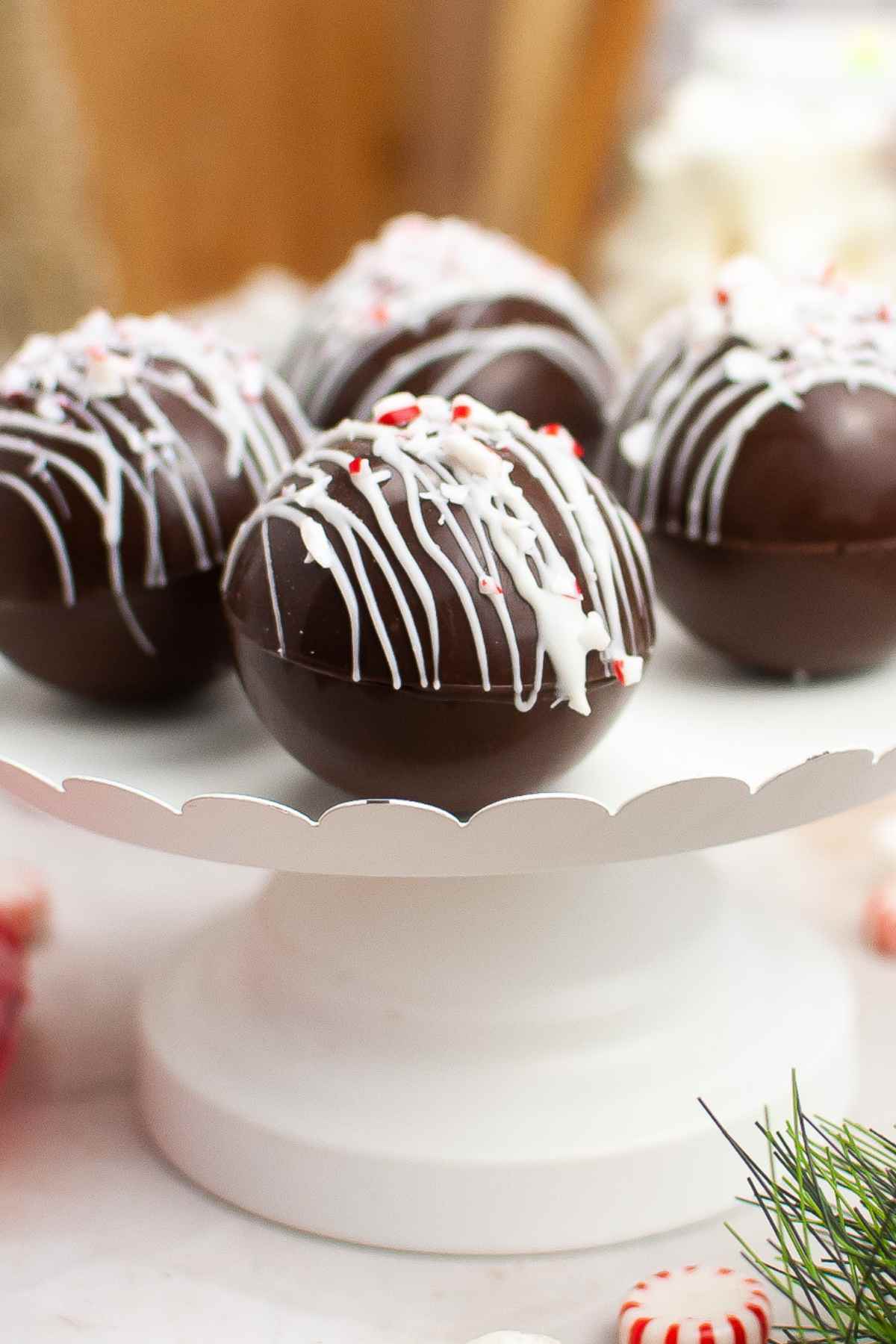 Side view of peppermint hot chocolate bombs on a white tray.