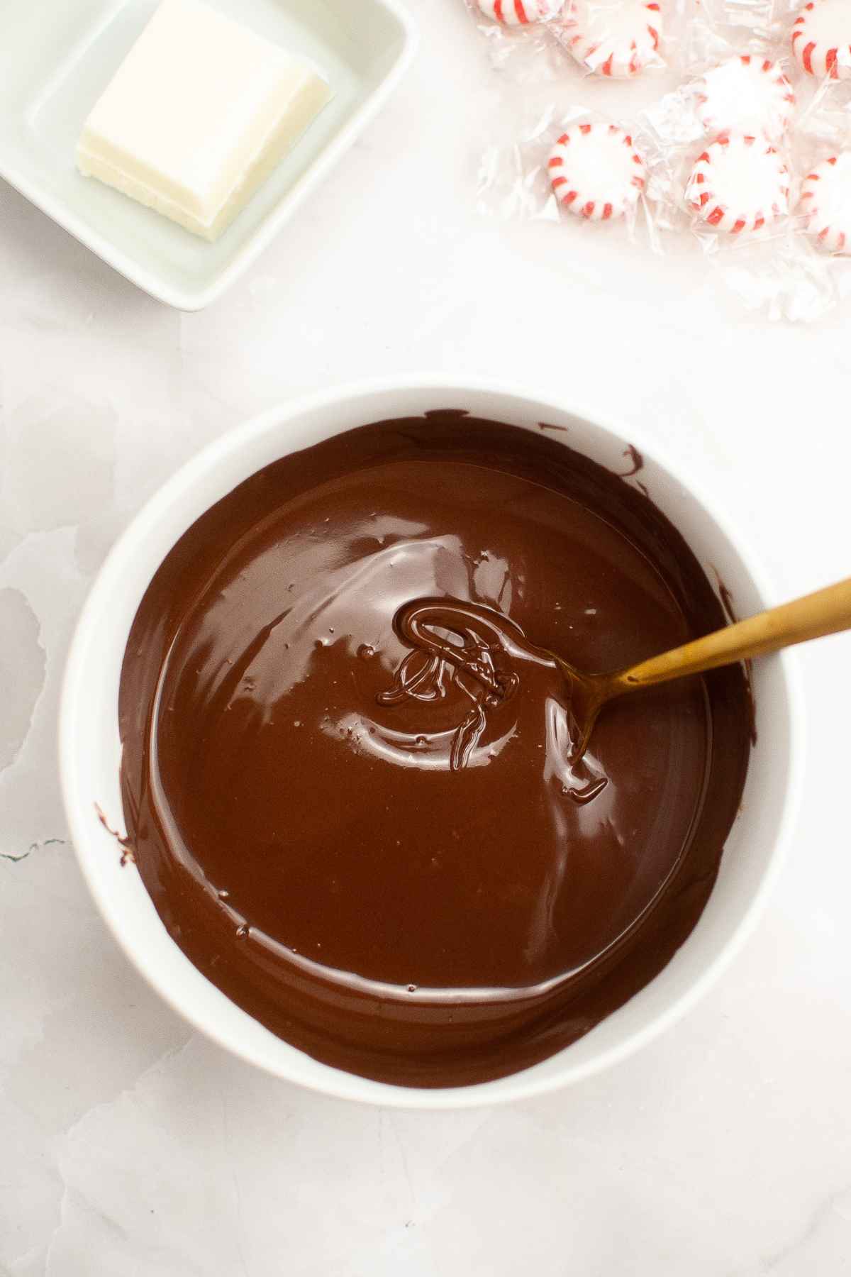 Melted milk chocolate wafers in a white bowl.