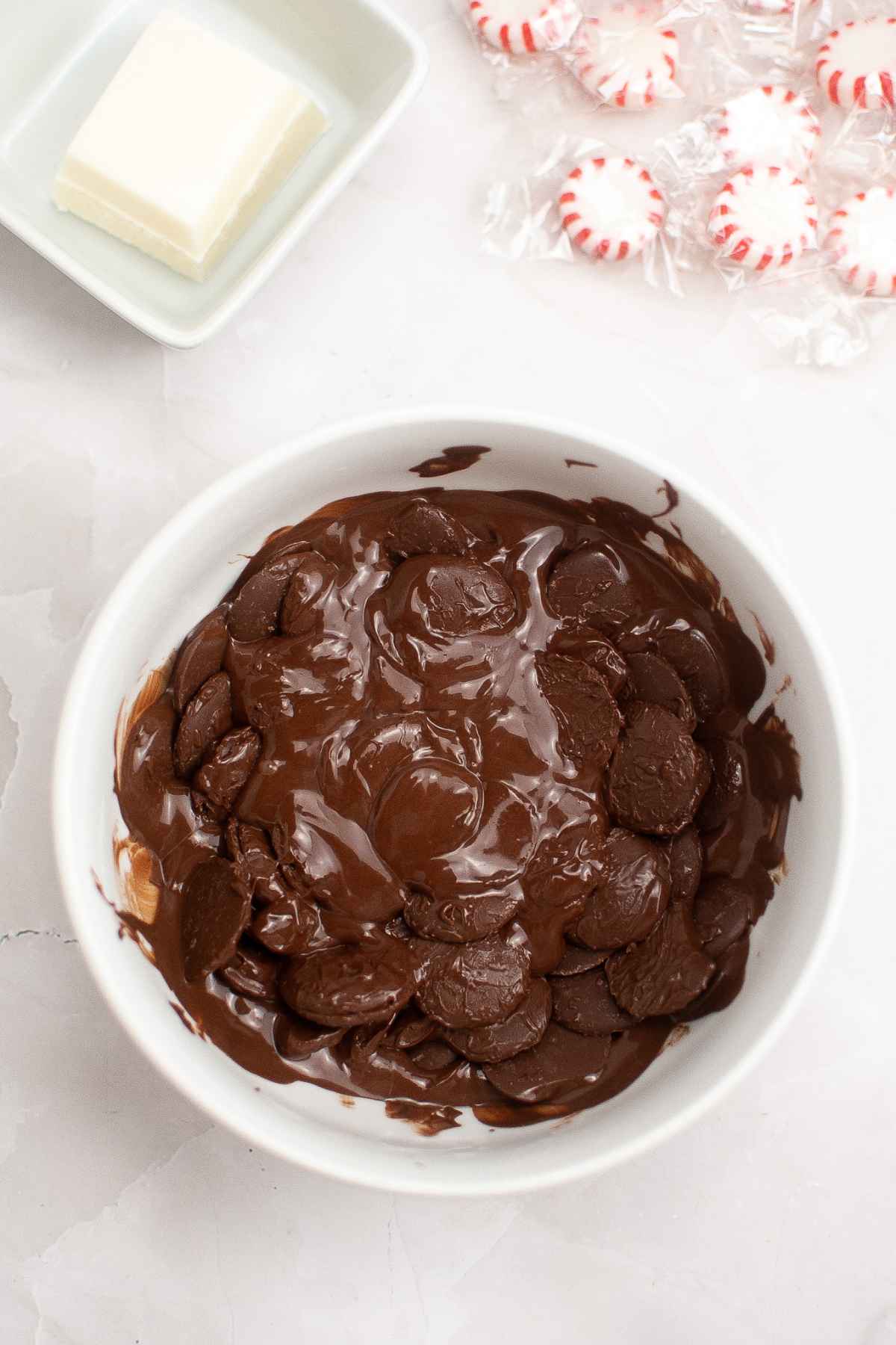 Partially melted chocolate wafers in a white bowl.