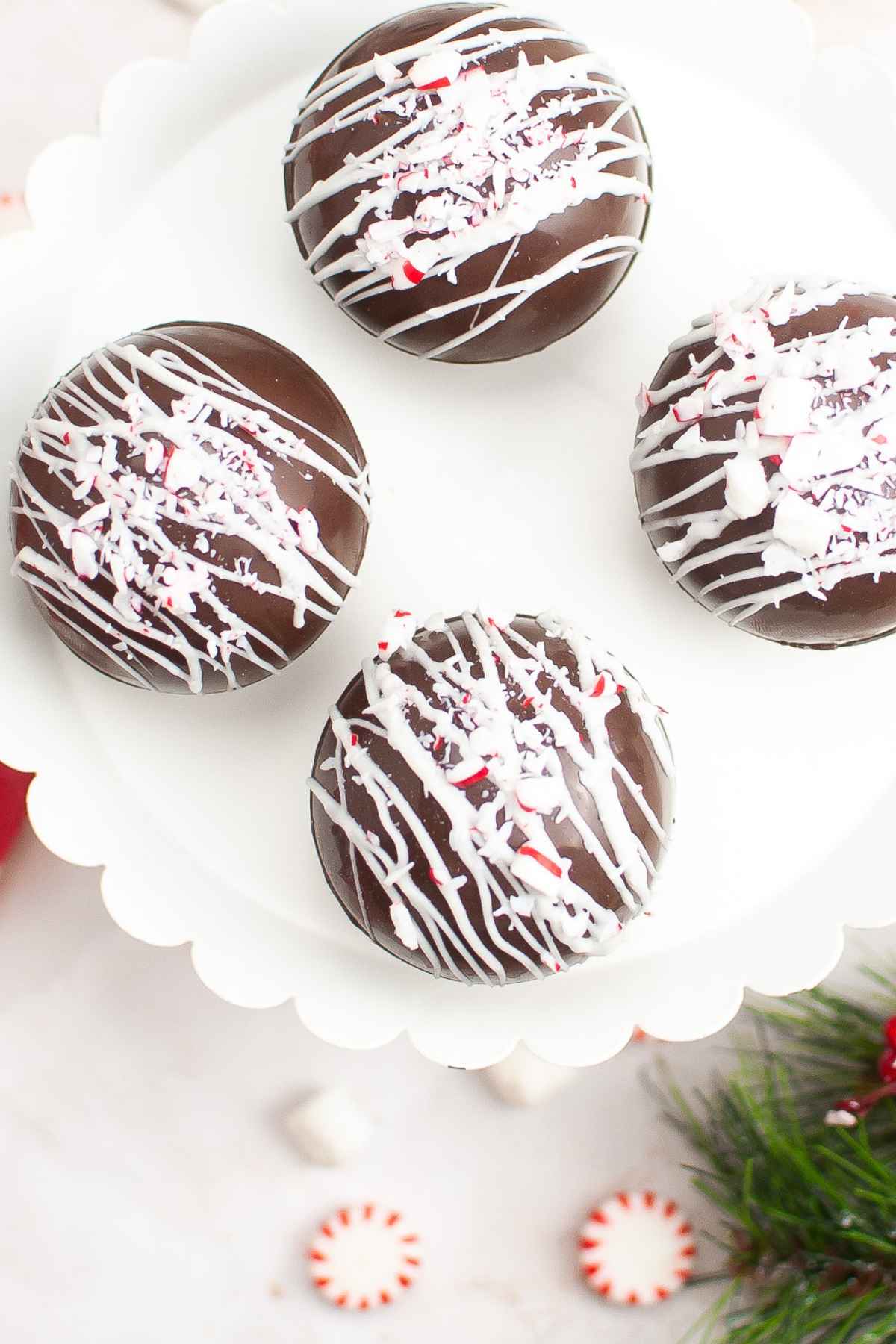 Overhead image of four hot cocoa bombs with white chocolate drizzle and crushed peppermint topping.