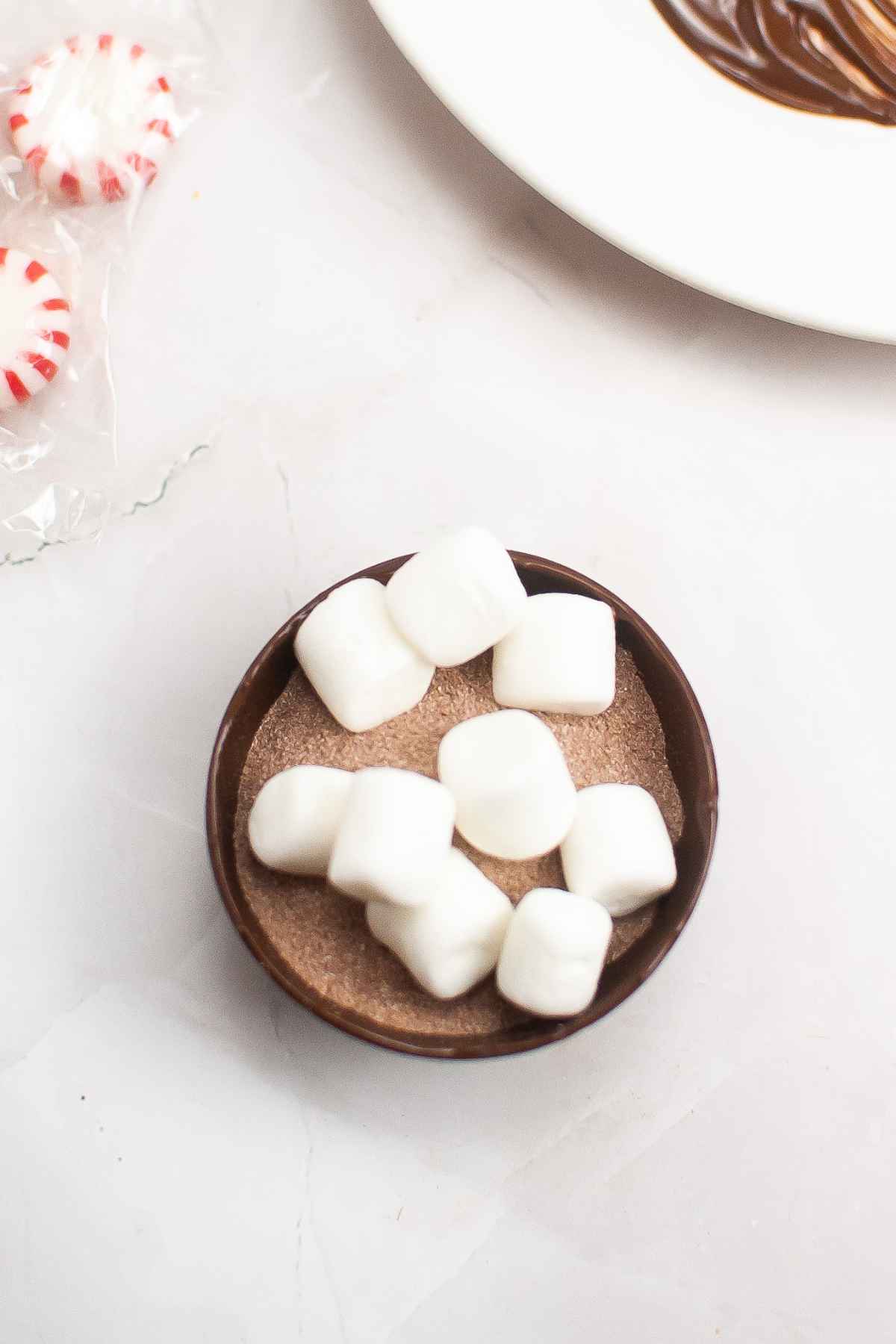 Half chocolate shell with cocoa mix and marshmallows.