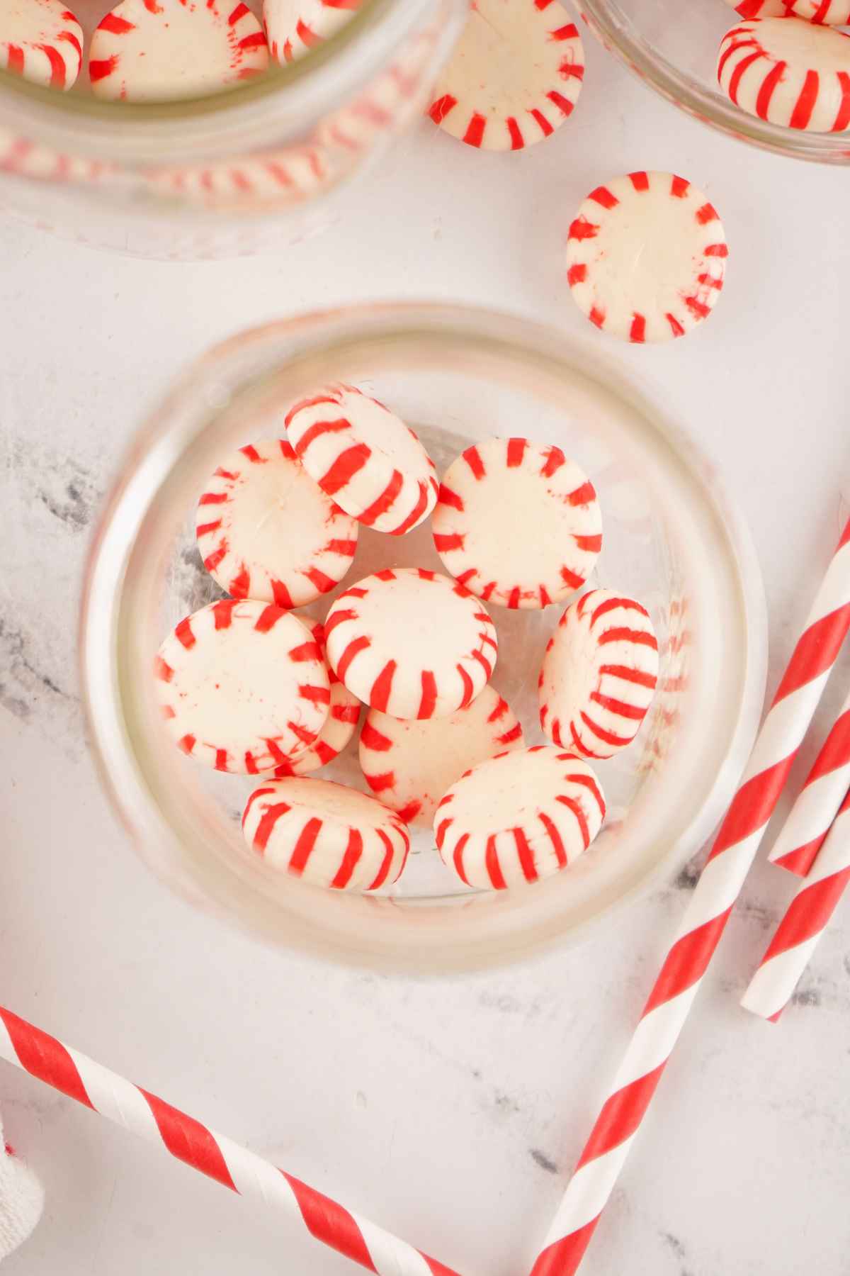 Overhead shot of unwrapped red and white mint candies in the mason jar.