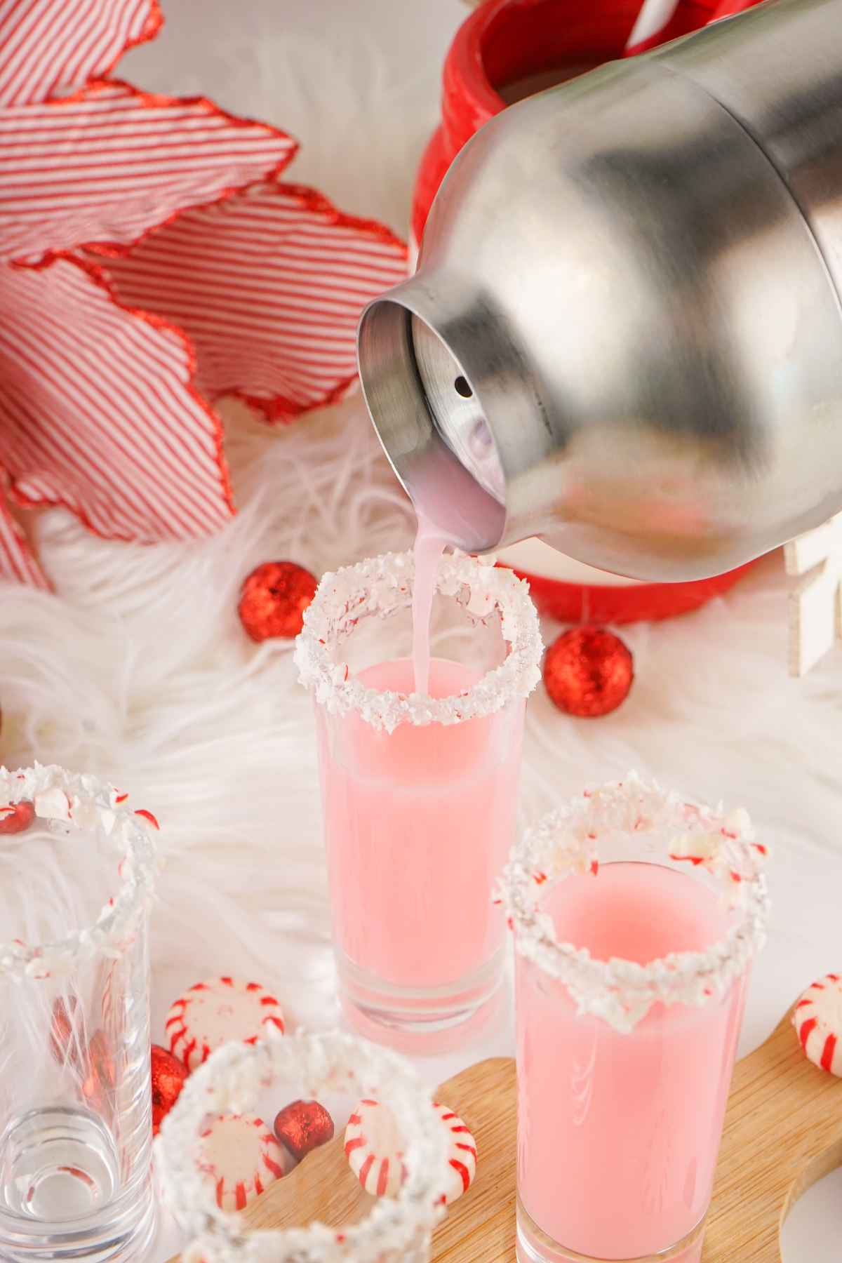 Pouring the chilled peppermint vodka into shot glasses rimmed with crushed peppermint candies.