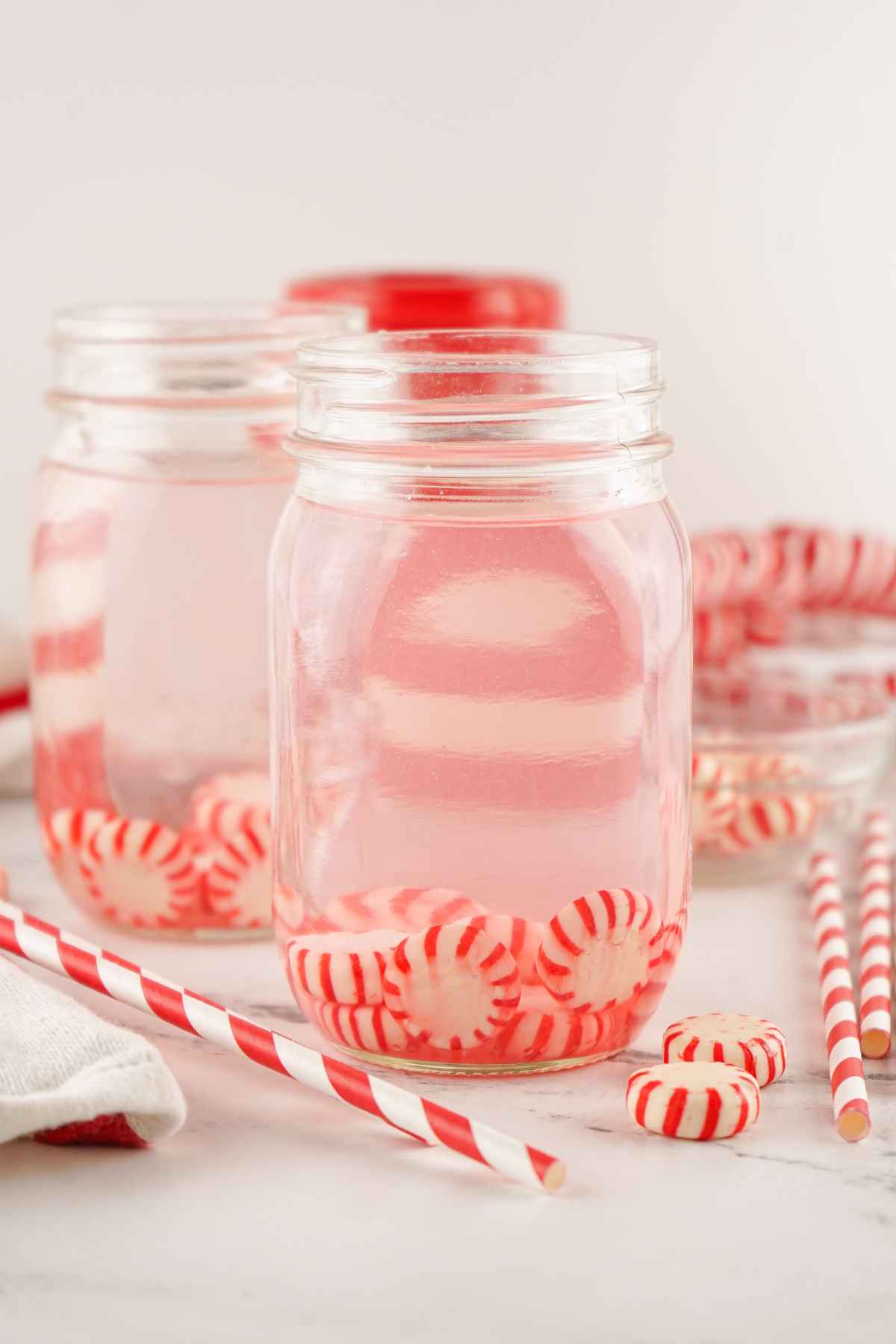 A mason jar filled with vodka and red and white hard candies.