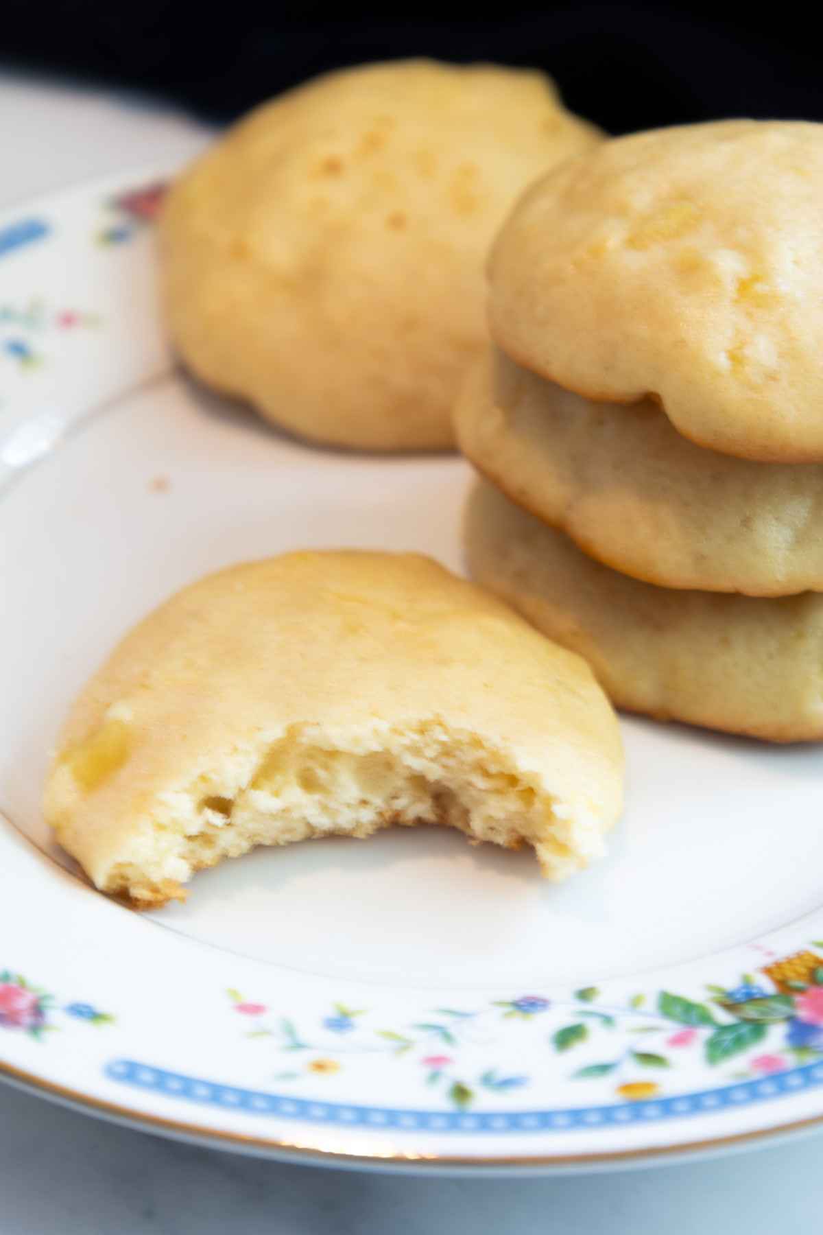 A plate with stacked cookies and one cookie with a bite taken from it.