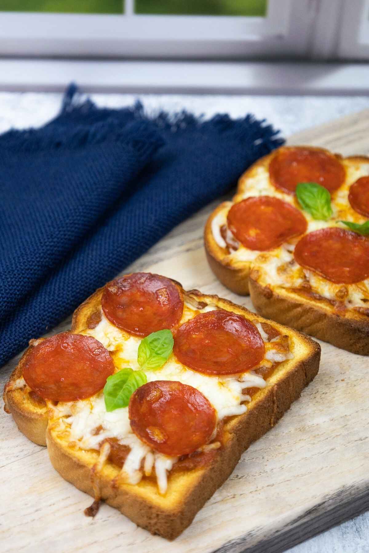 Two slices of pizza toast on a wooden board.