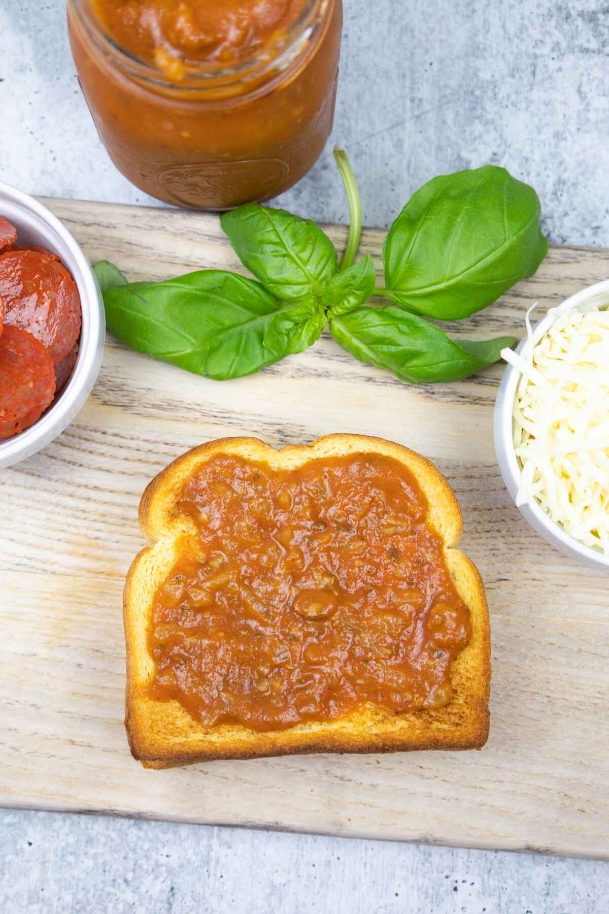 Tomato sauce layer on toasted bread.