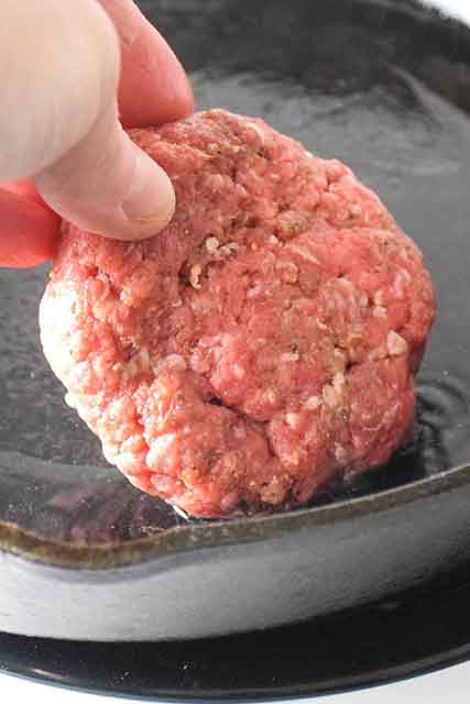 placing hamburger steak in hot skillet with oil