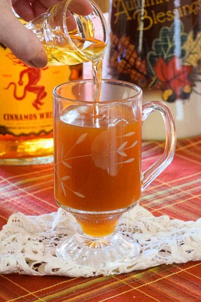 pouring a shot of fireball whisky into the hot apple cider
