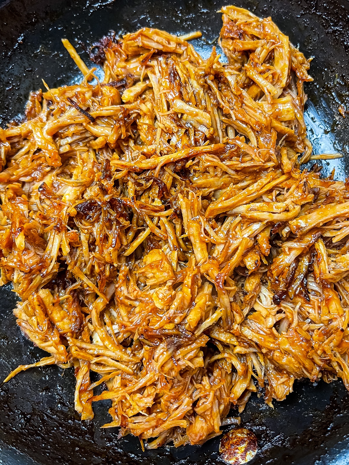 Pulled pork and barbecue sauce cooking in a skillet.