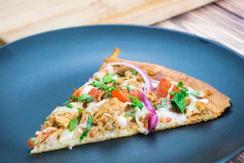 a slice of pulled pork pizza on a black plate