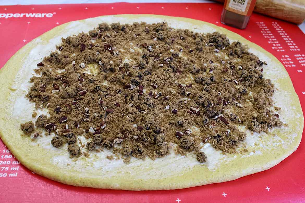 Cinnamon Sugar Mixture filling spread on top of roll dough.