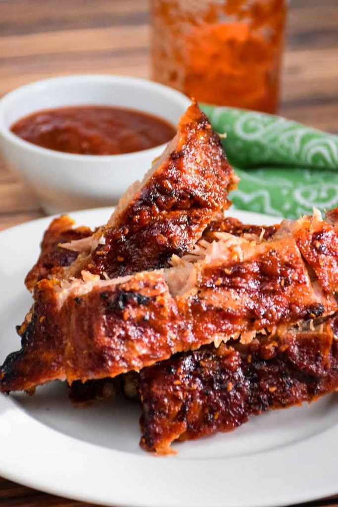 Pork Back Ribs on a plate with a small side of sugar-free Raspberry Chipotle Barbecue Sauce