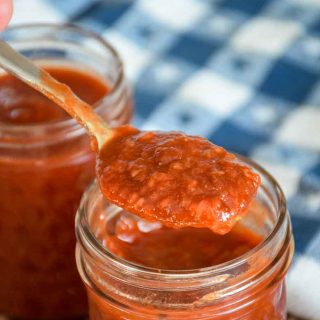 Raspberry Chipotle Sauce being spooned out of a jar with a white and blue star towel in the background