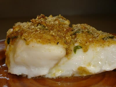 Thick red snapper fillet on a red plate with bread crumb topping.