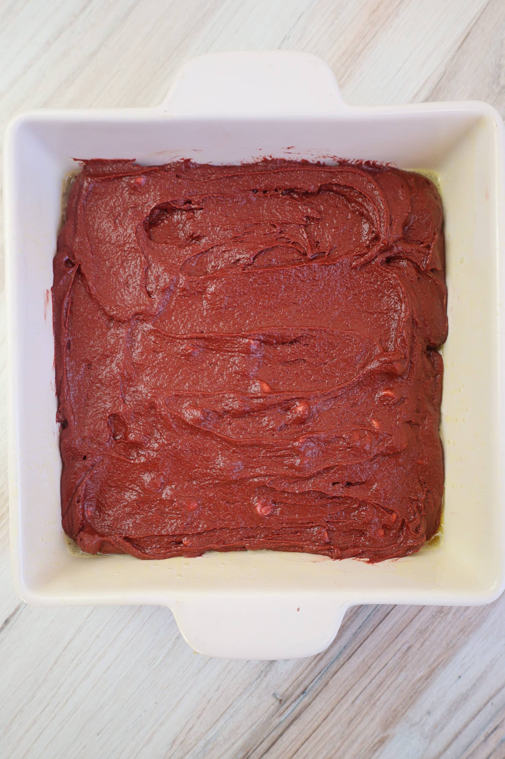 Unbaked brownie batter in a white baking dish.