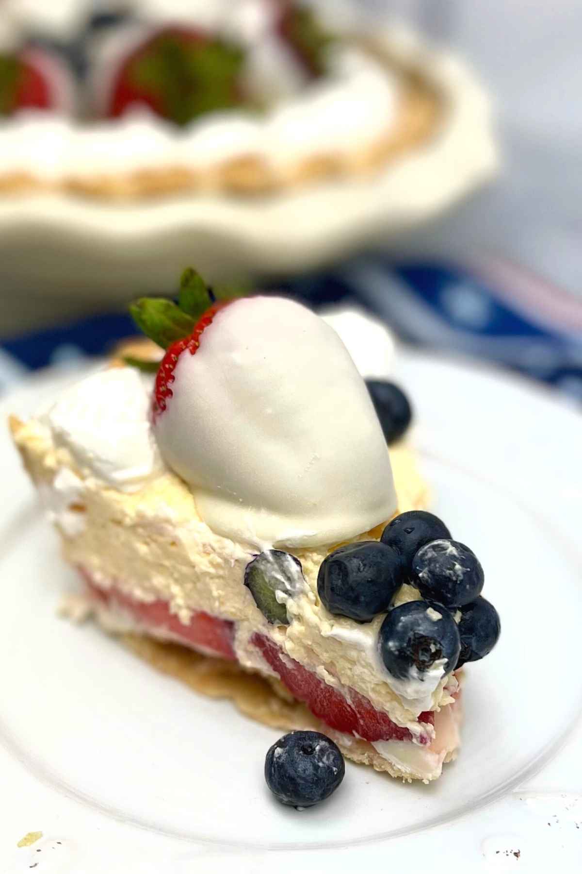 One slice of red white and bluebery pie on a white plate.