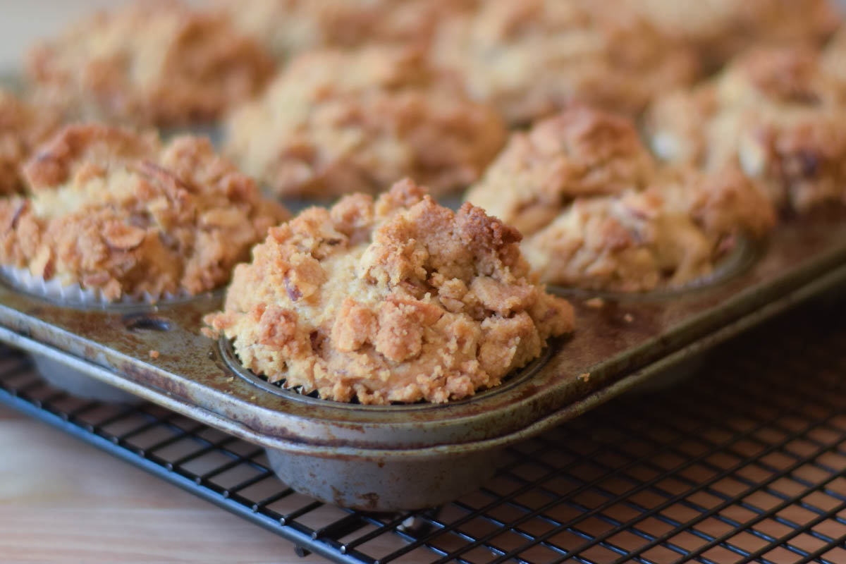 Baked muffins in a muffin pan cooling on a wire rack.