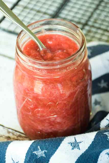 An open jar of rhubarb sauce recipe with a spoon in the jar.