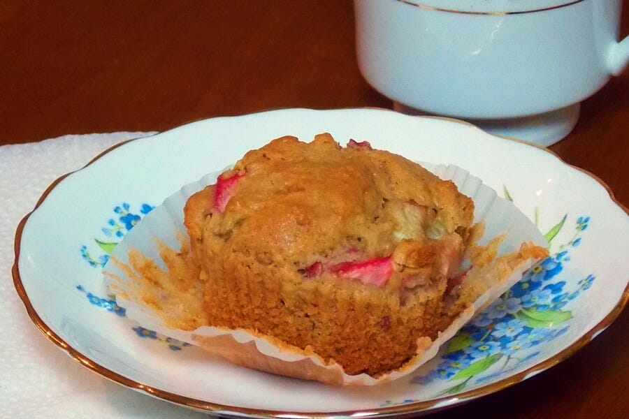 One muffin with the paper liner removed and sitting on top of the liner on a blue floral plate.