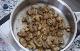 Fried mushrooms with umami seasoning sprinkled on to in a stainless steel skillet