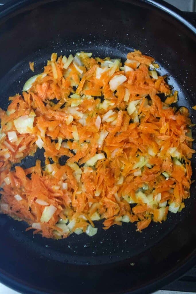 Shredded carrots and onions in a skillet.