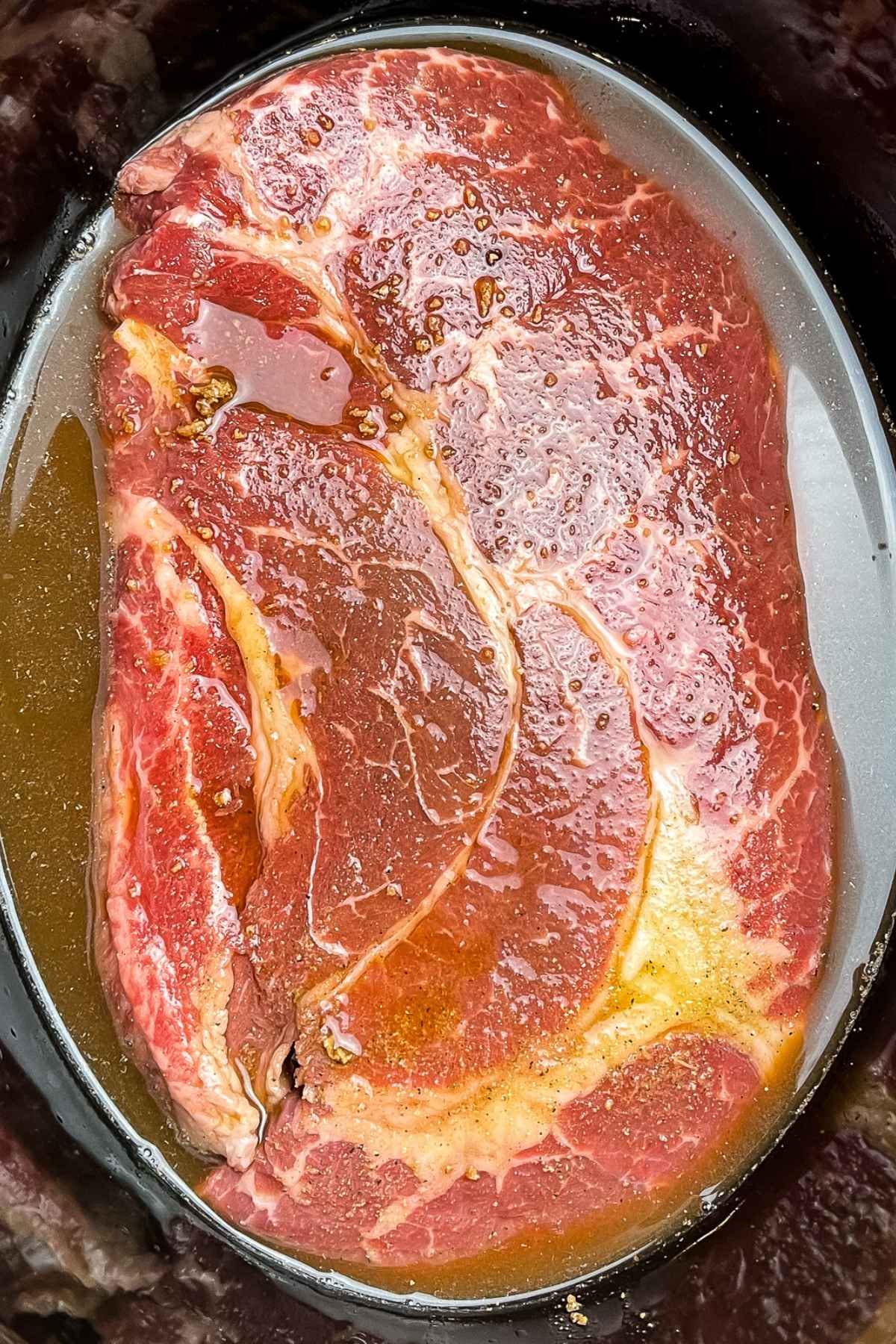 Chuck roast in slow cooker with broth mixture.