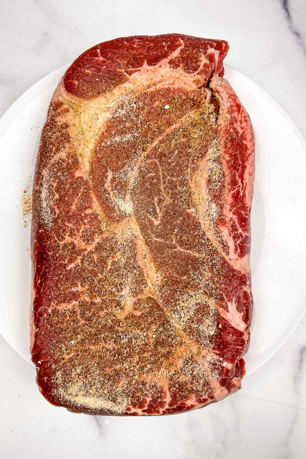 Seasoned chuck roast on a white plate.