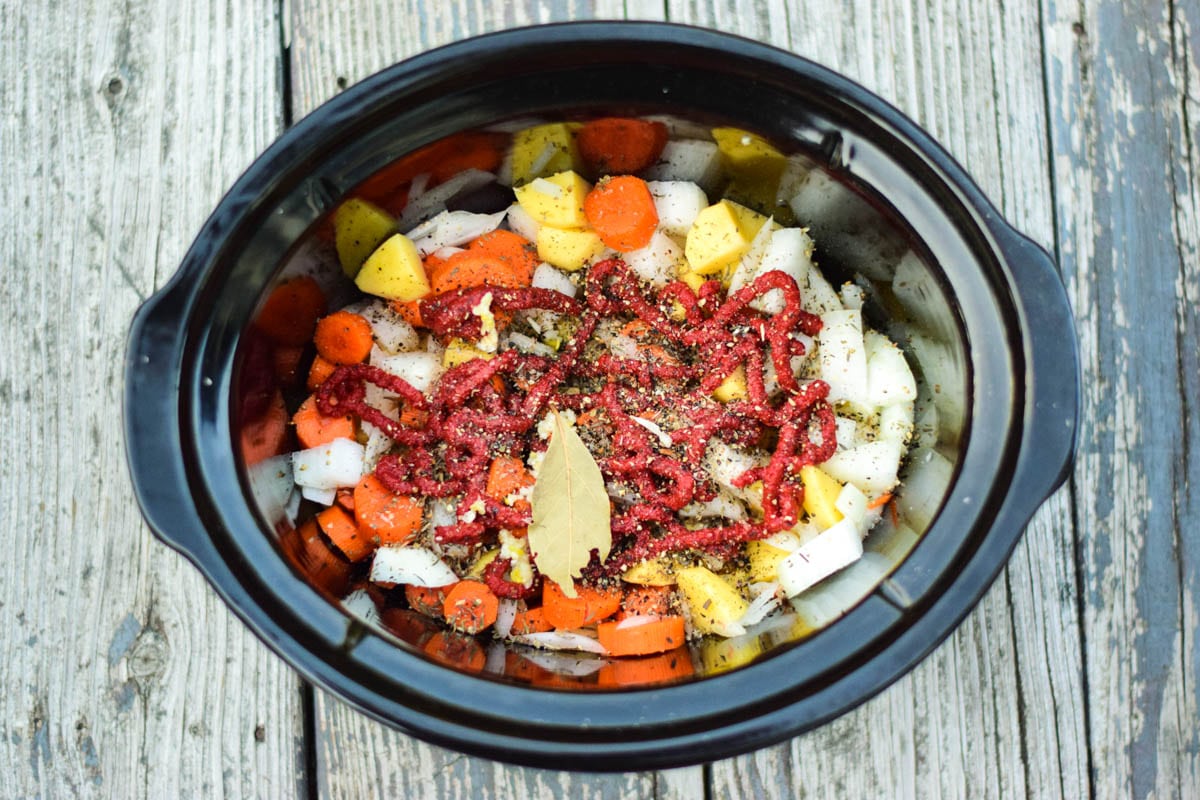 Layered potatoes, carrots, and spices in slow cooker.
