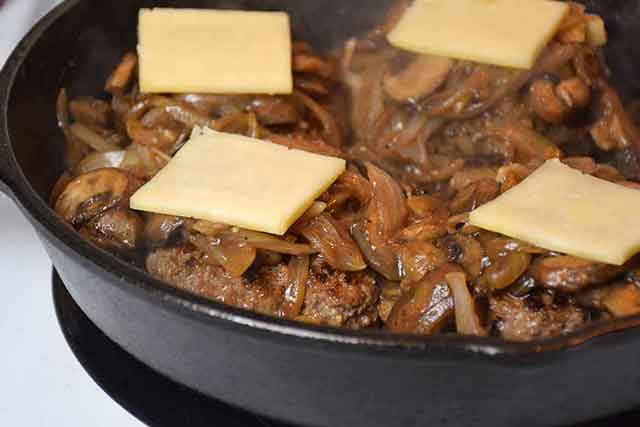 Smothered Hamburger Steaks with Onions and Mushrooms and cheese on top.