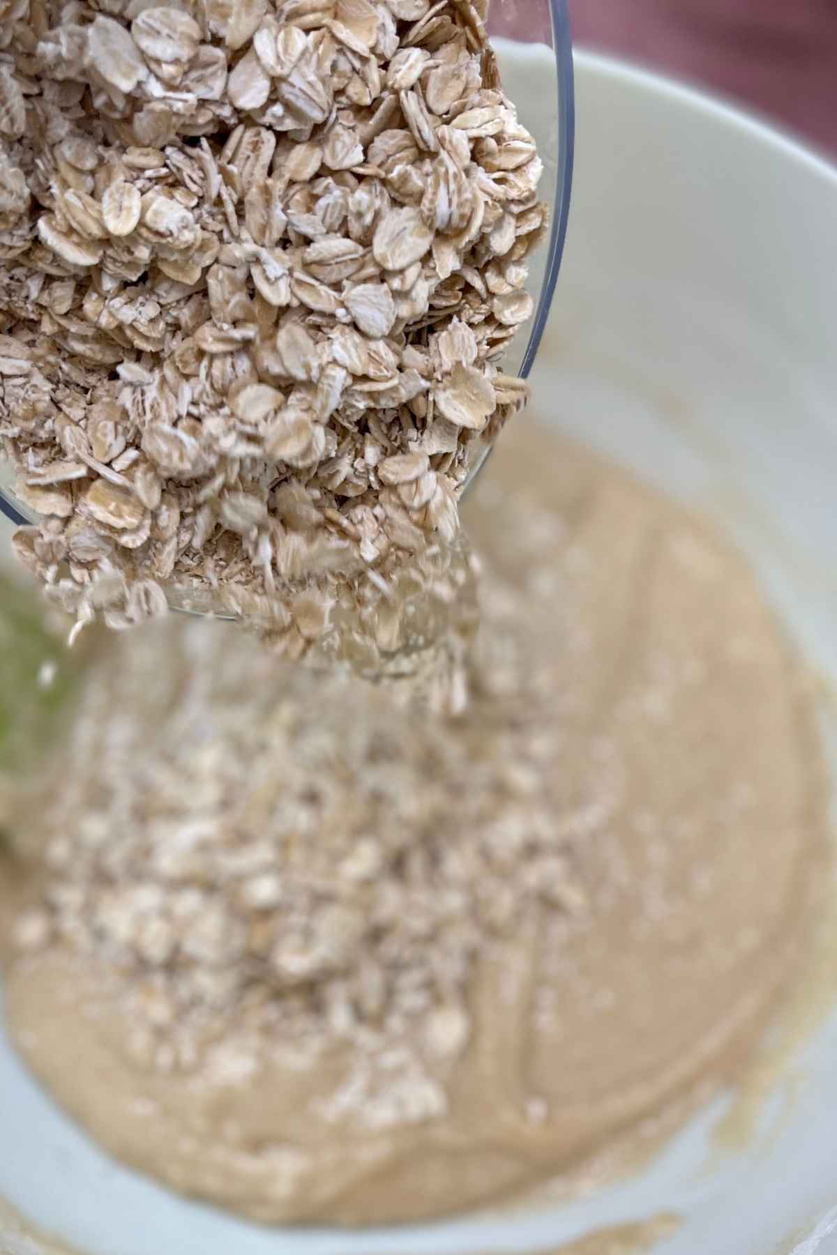 Pouring oats into cookie batter.