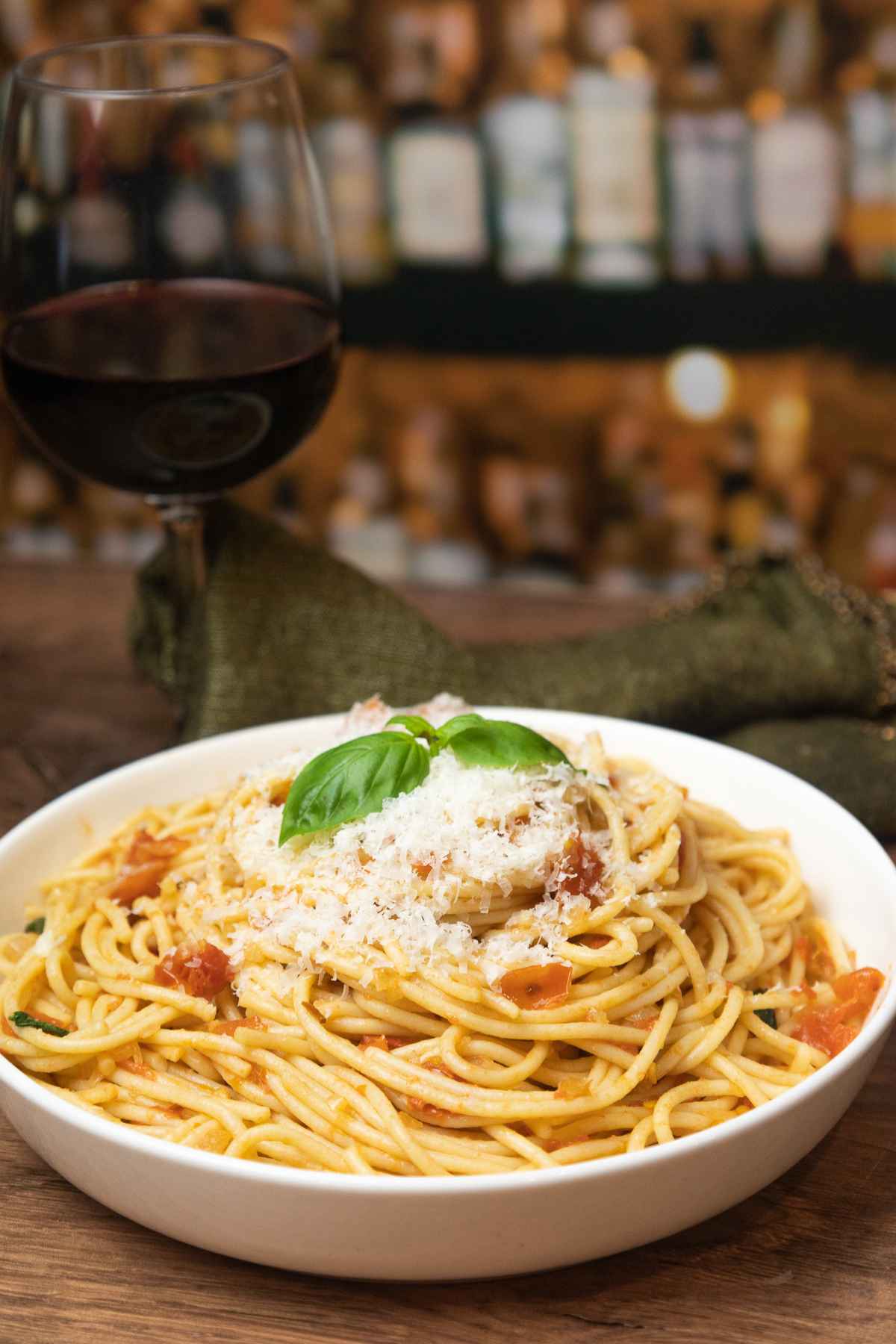 Side view of pasta dish topped with grated parmesan cheese and fresh basil.