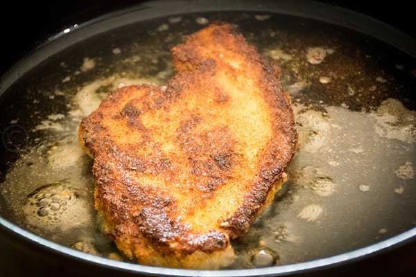 Golden brown chicken frying in a skillet.