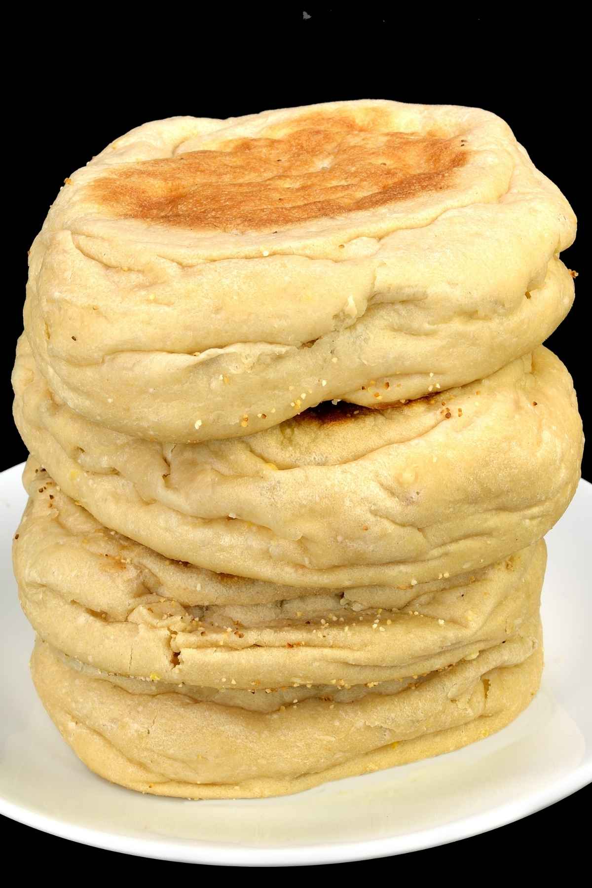 A stack of 3 English muffins on a white plate.