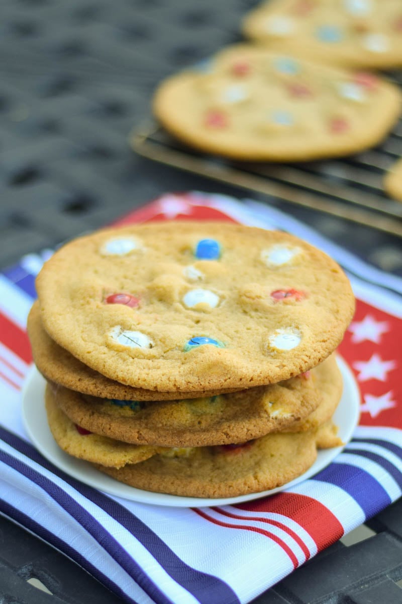 A plate with a stack of chewy m and m cookies.