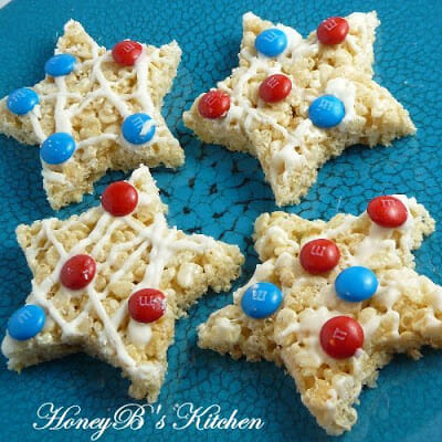Four rice krispie treats cut into star shapes and decorated with red white and blue m&m candy.